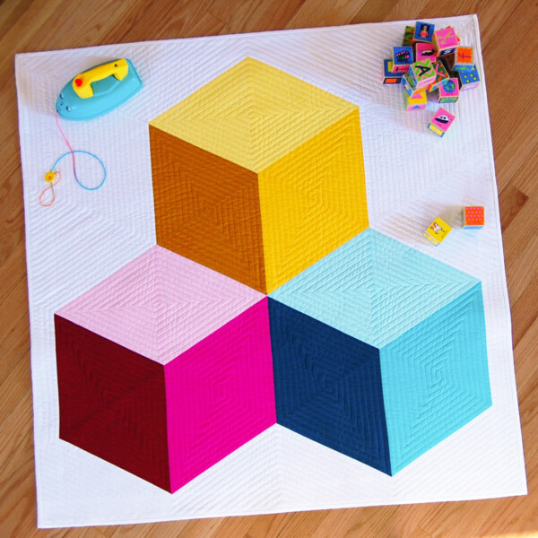 Yellow, pink and blue stacked blocks baby quilt with toys